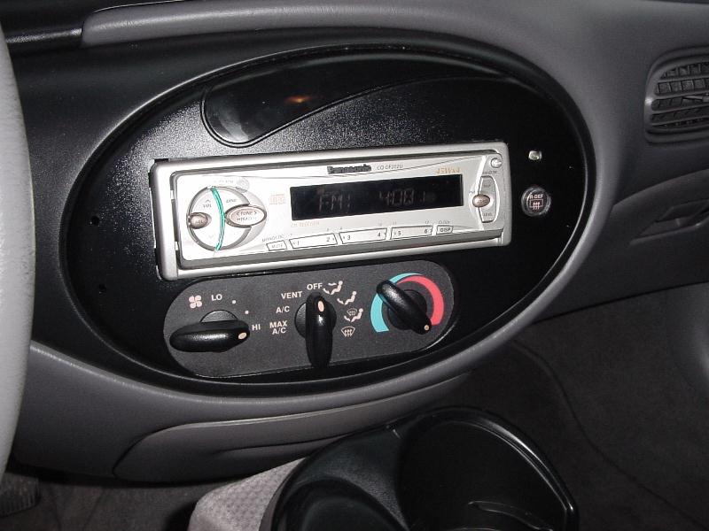Aftermarket head unit in oval dash bezel with rotary HVAC controls, gray interior