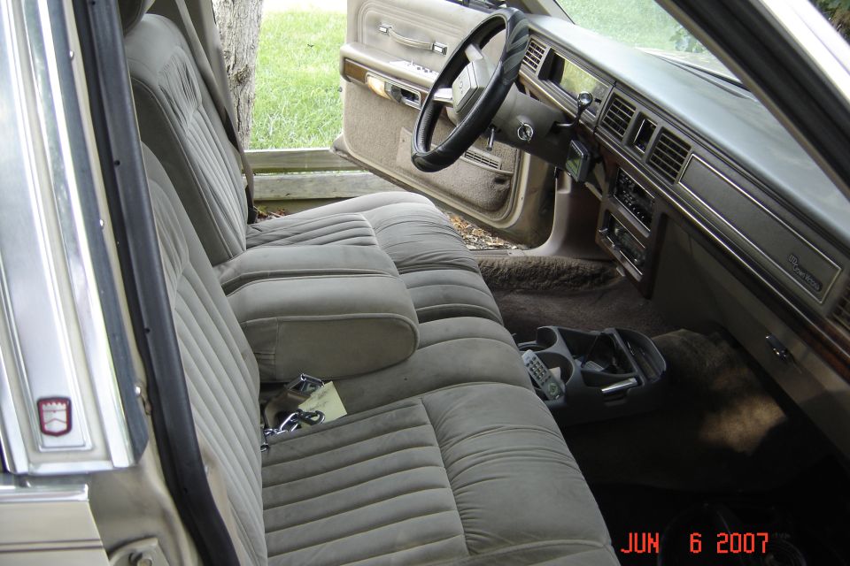 Tan cloth front bench seat and dashboard inside an older sedan