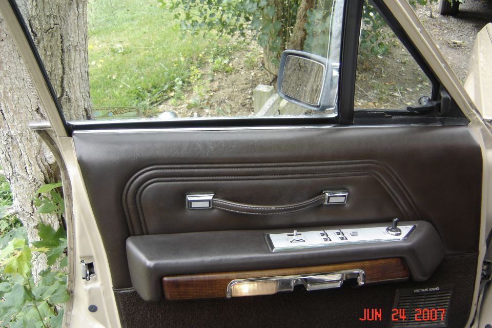 Brown leather door panel with chrome pull handle inside an older car