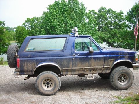 1994 Ford Bronco - This blue Ford Bronco is covered in mud, suggesting it has been off-roading.