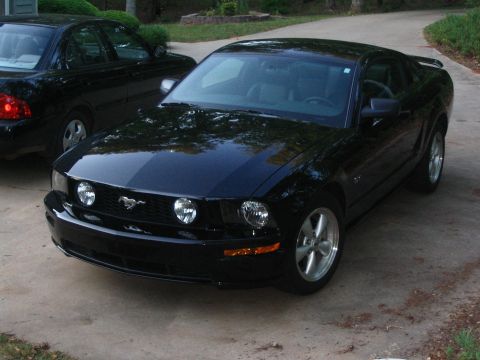 2007 Ford Mustang - A black Ford Mustang is parked on a concrete driveway, with another car visible behind it.