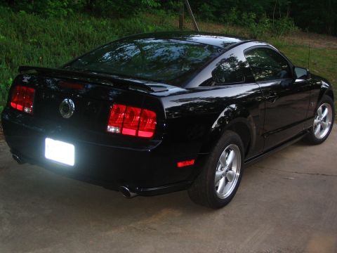 2007 Ford Mustang - A black Ford Mustang coupe is shown from the rear three-quarter angle, parked outdoors.