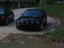 2007 Ford Mustang - Front view of a black 2007 Ford Mustang parked on a paved surface with grass and trees.