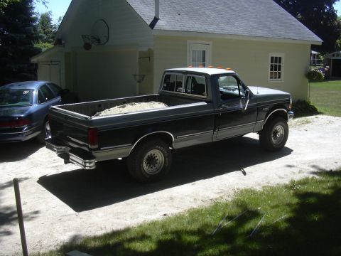 1992 Ford F-250 - A Ford F-250 pickup truck is parked next to a house and garage, with a sedan visible on the left.