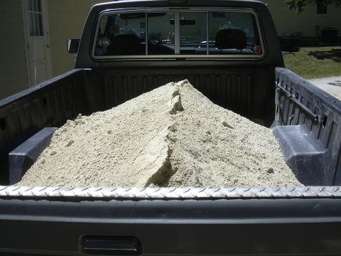 1992 Ford F-250 - Rear view of a 1992 Ford F-250 pickup truck bed filled with a large pile of sand.