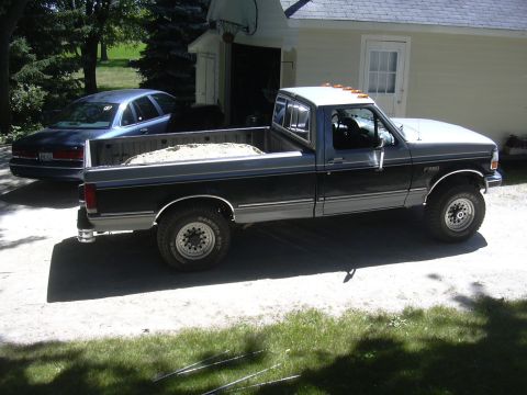 1992 Ford F-250 - A two-tone Ford F-250 pickup truck is parked in front of a house with a blue sedan behind it.
