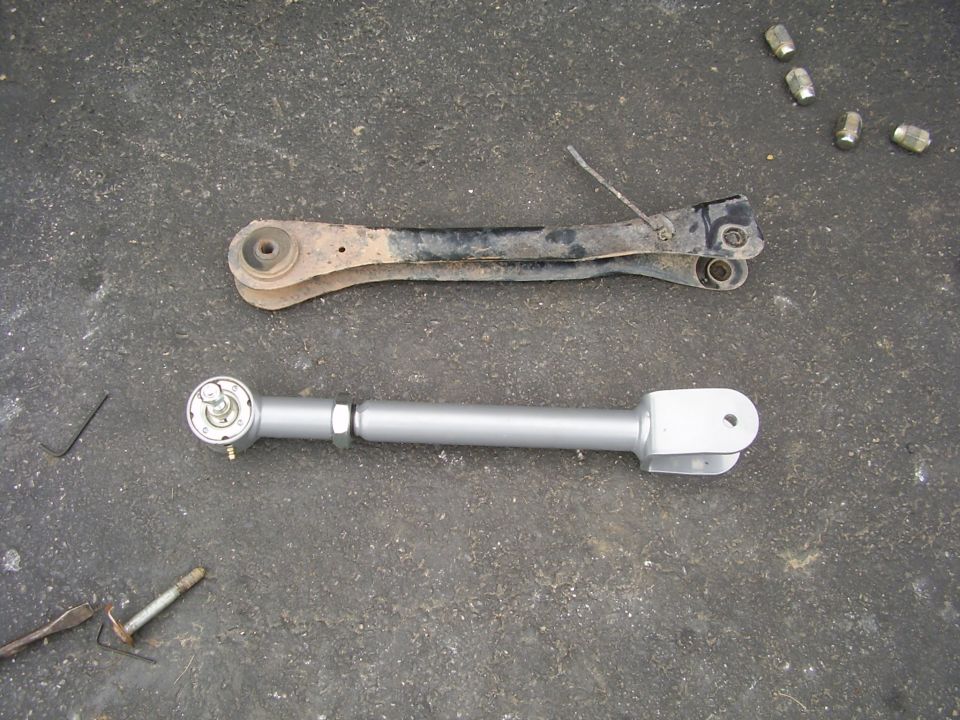 old control arm next to a new adjustable one