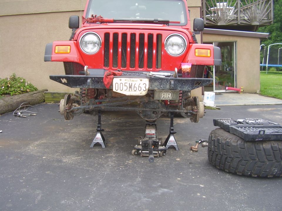 Red 2003 Jeep Wrangler front end on jack stands, license plate 005M663