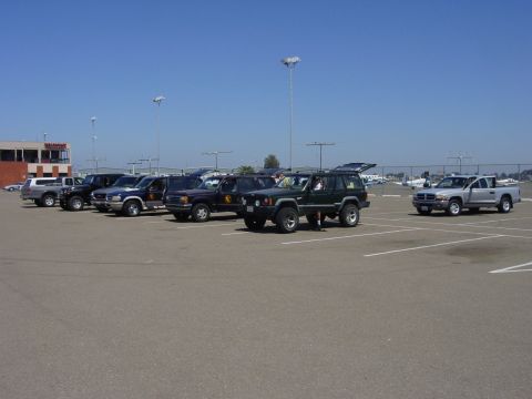 1994 Ford Bronco - A group of SUVs and trucks are parked in an outdoor lot on a sunny day.