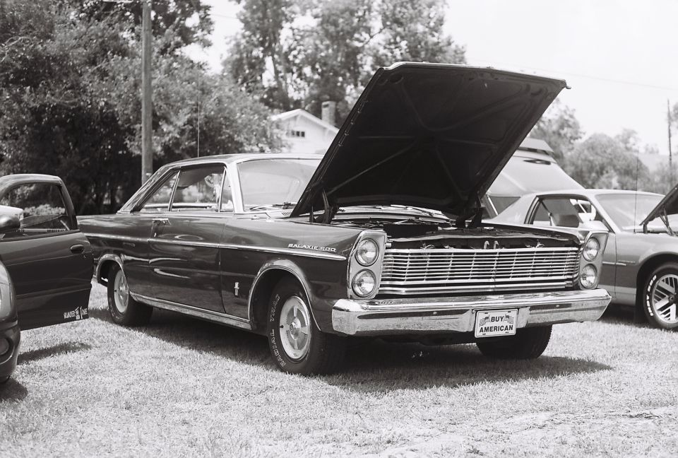 1965 Ford Galaxie 500 with hood open, front 3/4 view, dark color