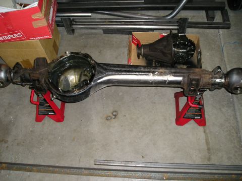 1986 Toyota Hilux - A bare rear axle housing supported on two red jack stands, with the differential center section removed and set on a Staples cardboard box…
