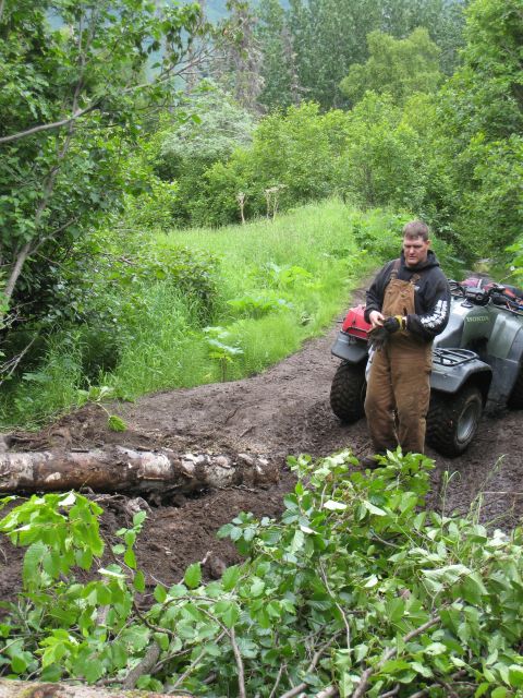 2000 Ford E350 - Man and ATV on a muddy trail with a fallen log blocking the path.