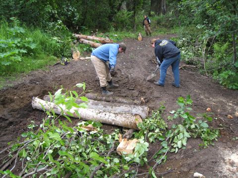 2000 Ford E350 - People are working on a dirt path, moving logs and dirt with shovels.