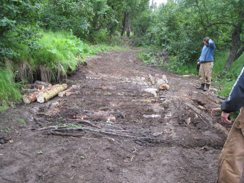 2000 Ford E350 - The trail is being cleared and built up with logs and dirt in a wooded area.