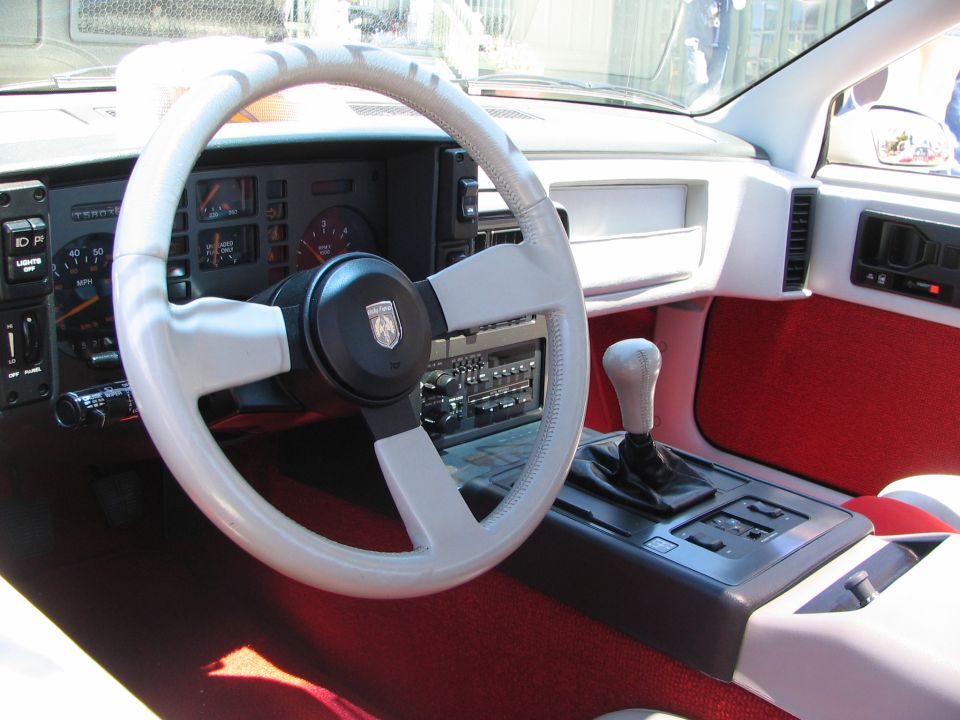 1986 Pontiac Fiero interior with white steering wheel and red carpet
