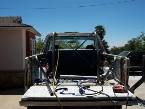 1995 Ford Bronco - The rear of a pickup truck is shown with a newly installed roll cage and various tools in the bed.