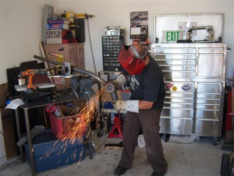 1995 Ford Bronco - A person works on metal fabrication in a garage, surrounded by tools and equipment.