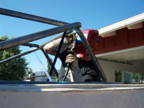 1995 Ford Bronco - A person in a welding mask works on a metal rollcage structure outdoors.