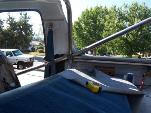 1995 Ford Bronco - Interior view showing a roll cage and seatbelt, with a white Ford Bronco visible through the window.