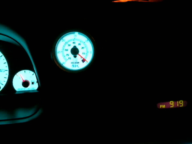 Glowing white-face gauges at night with aftermarket vacuum gauge and clock reading 9:19 PM