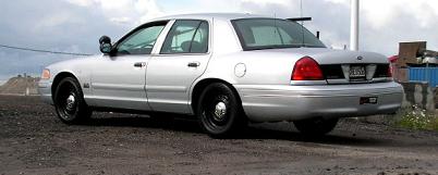 1998 Ford Crown Victoria - This 1998 Ford Crown Victoria is shown from the rear quarter angle, parked on a dirt surface with a cloudy sky.