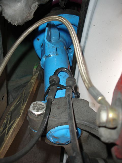 1993 Ford Taurus - Close-up view of a blue shock absorber assembly, showing braided brake lines and suspension components.