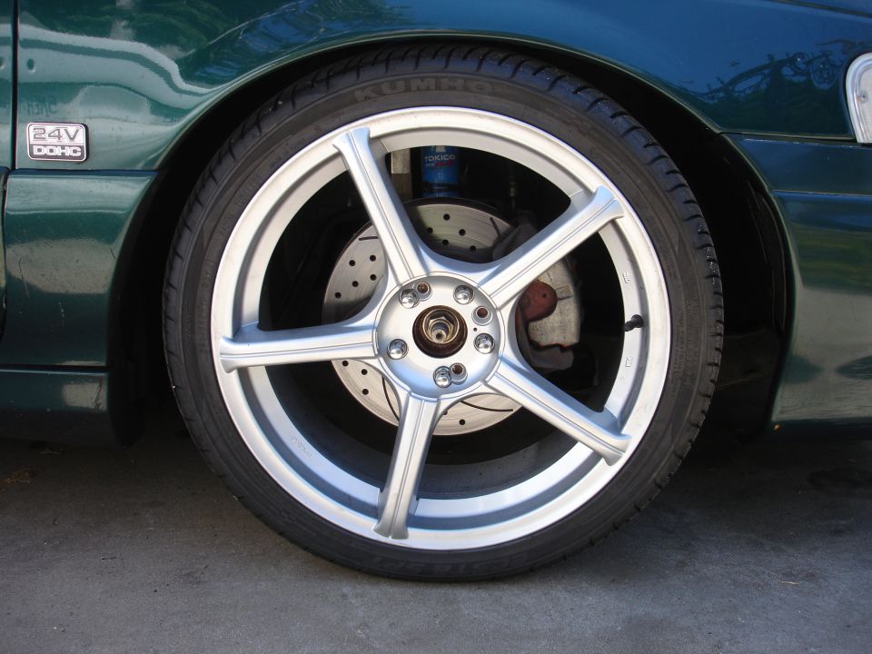Silver five-spoke wheel with Kumho tire, drilled rotor, red caliper and blue Tokico strut