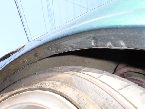 1993 Ford Taurus - Close-up view of a car's wheel well, showing the tire and suspension components.