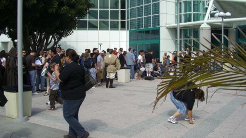 1990 Ford Probe - A large gathering of people, some dressed in costumes, are waiting outside a modern building.