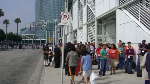 1990 Ford Probe - A large group of people are waiting outside a convention center, with palm trees and a modern building visible.