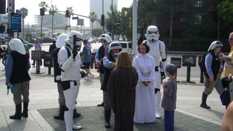 1990 Ford Probe - A group of individuals dressed as Star Wars characters, including Stormtroopers and Princess Leia, are seen interacting in an outdoor urban…