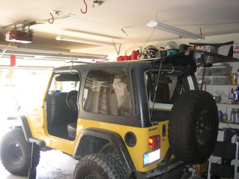 2001 Jeep Wrangler - Yellow 2001 Jeep Wrangler in a garage, showing its interior and open tailgate with a spare tire mounted.