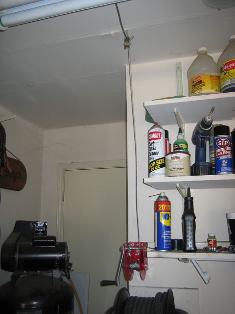 2001 Jeep Wrangler - A garage scene displays a hoist, shelves filled with car maintenance supplies, and an air compressor.