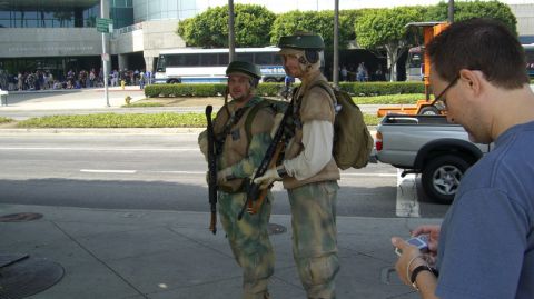 1990 Ford Probe - Two individuals in military-style costumes stand with rifles outside a convention center, with a pickup truck visible in the background.