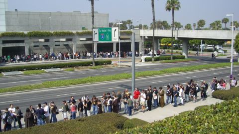 1990 Ford Probe - A white SUV is visible near a freeway entrance where a large group of people are gathered.