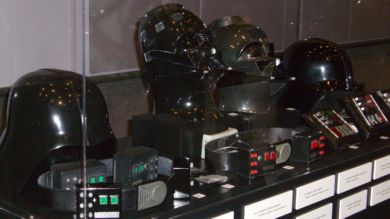 Several Darth Vader helmets and costume parts displayed on a shelf