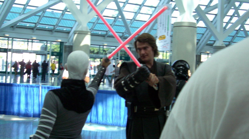 Two people in Star Wars costumes are dueling with lightsabers indoors