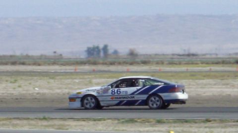 1990 Ford Probe - A race car with blue stripes and the number 86 is seen on a track.