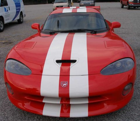 1998 Ford Crown Victoria - A red Dodge Viper with dual white racing stripes is seen from the front, with other vehicles in the background.