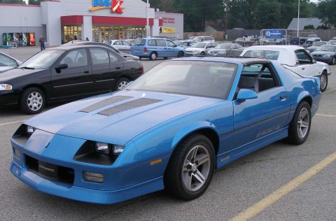 1998 Ford Crown Victoria - A blue Chevrolet Camaro is parked in a lot in front of a Kmart store.