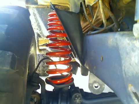 1979 Ford Bronco - Close-up view of a red coil spring and suspension components on a vehicle.