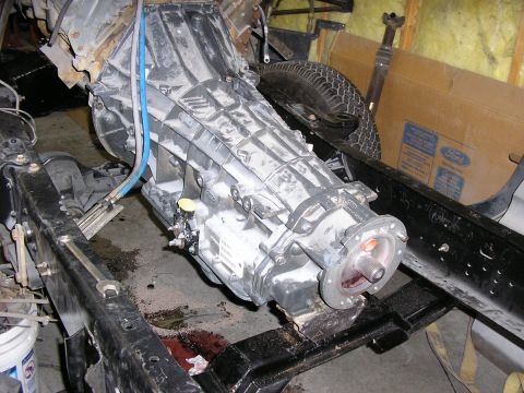 1979 Ford F-350 - A truck's transmission is shown removed from the chassis, with a spare tire and driveshaft in the background.