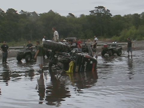 1976 Chevrolet Blazer - Off-road vehicle overturned in water with ATVs and spectators present.
