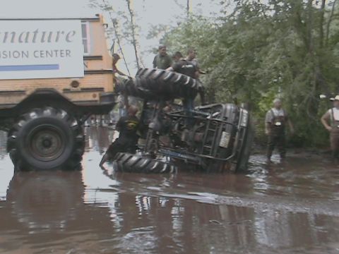 1976 Chevrolet Blazer - An ATV has overturned in a muddy area, with several people observing the scene.