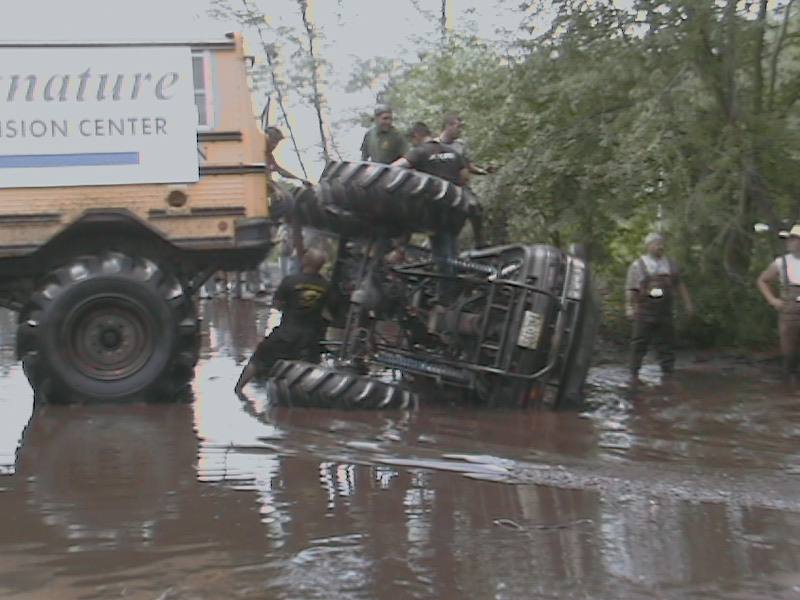 Overturned ATV in mud with people around