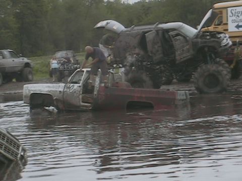 1976 Chevrolet Blazer - Multiple off-road vehicles participate in a mud bogging event, with one truck being worked on in the water.