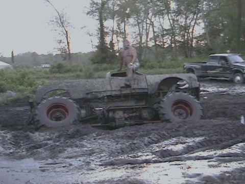 1976 Chevrolet Blazer - Custom vehicle stuck deep in mud during an off-road event, with a pickup truck nearby.