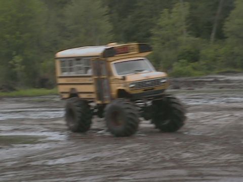 1976 Chevrolet Blazer - This modified school bus, equipped with massive tires, navigates a muddy off-road course.