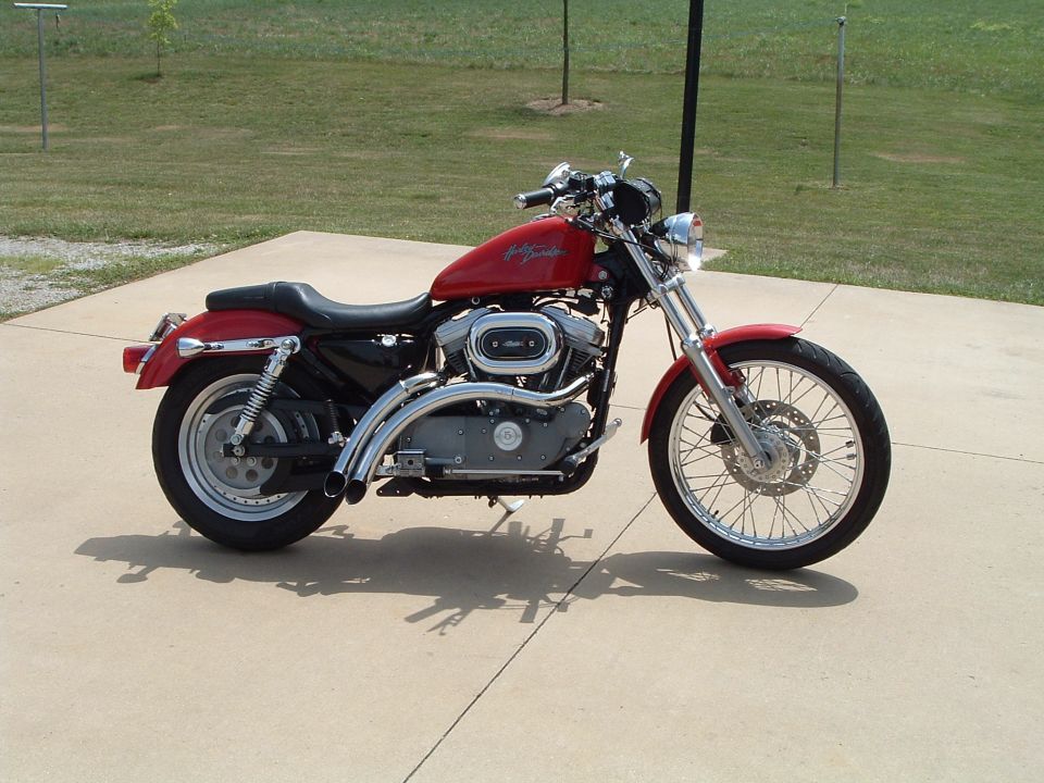 Red Harley-Davidson Sportster motorcycle, left-side view, parked on concrete