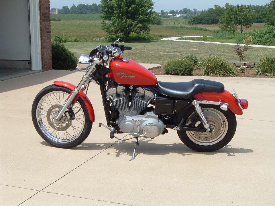 Red Harley-Davidson Sportster motorcycle parked on driveway, left side view